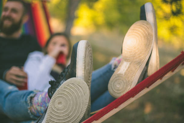 person relaxing in hammock diagonal position reading book listening to music park