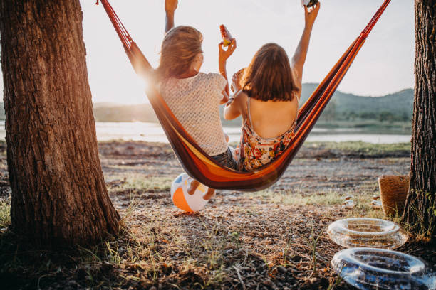 couple relaxing together in spacious double hammock lakeside camping sunset