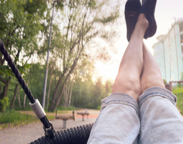 close up of feet in hammock swinging in city park relaxation concept