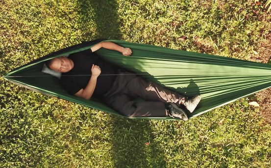 The man slept peacefully in the green hammock.