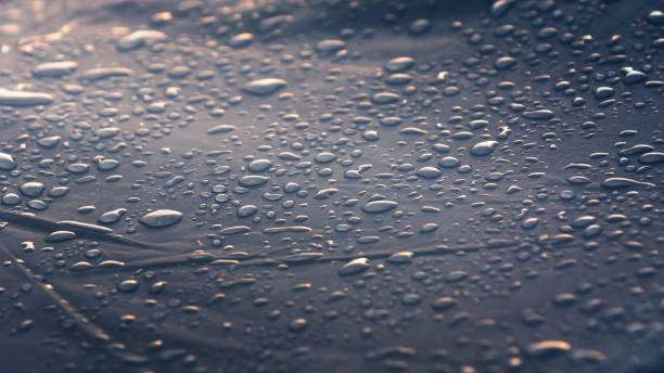 Raindrops on a durable, dark fabric, possibly a waterproof hammock cover or tarp.