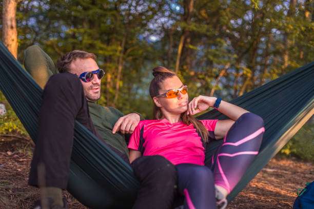 Boy and girl camping in forest, laying in hammock
