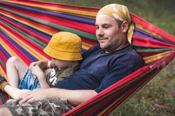 happy family with children relaxing in a hammock in a green backyard summer day