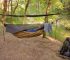 Modern camping hammock with mosquito netting in a wilderness campsite near a stream